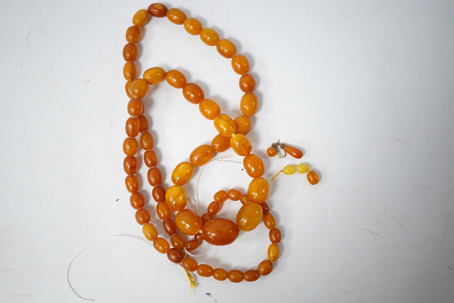 A single strand graduated oval amber bead necklace (a.f.), 90cm, gross weight 72 grams and three odd beads and an earring. Condition - poor